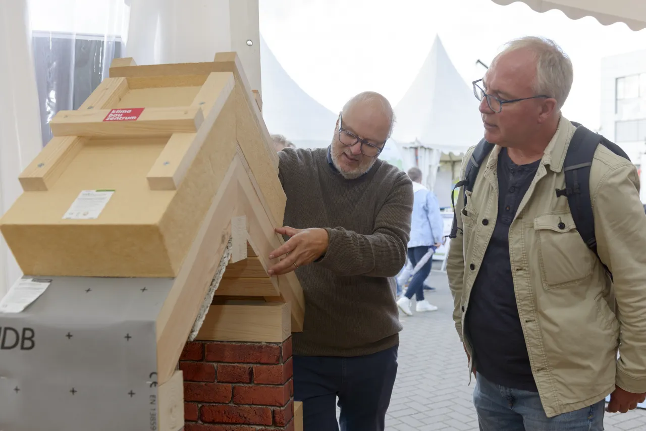 Zwei M&auml;nner schauen sich ein D&auml;mm-Modell an
